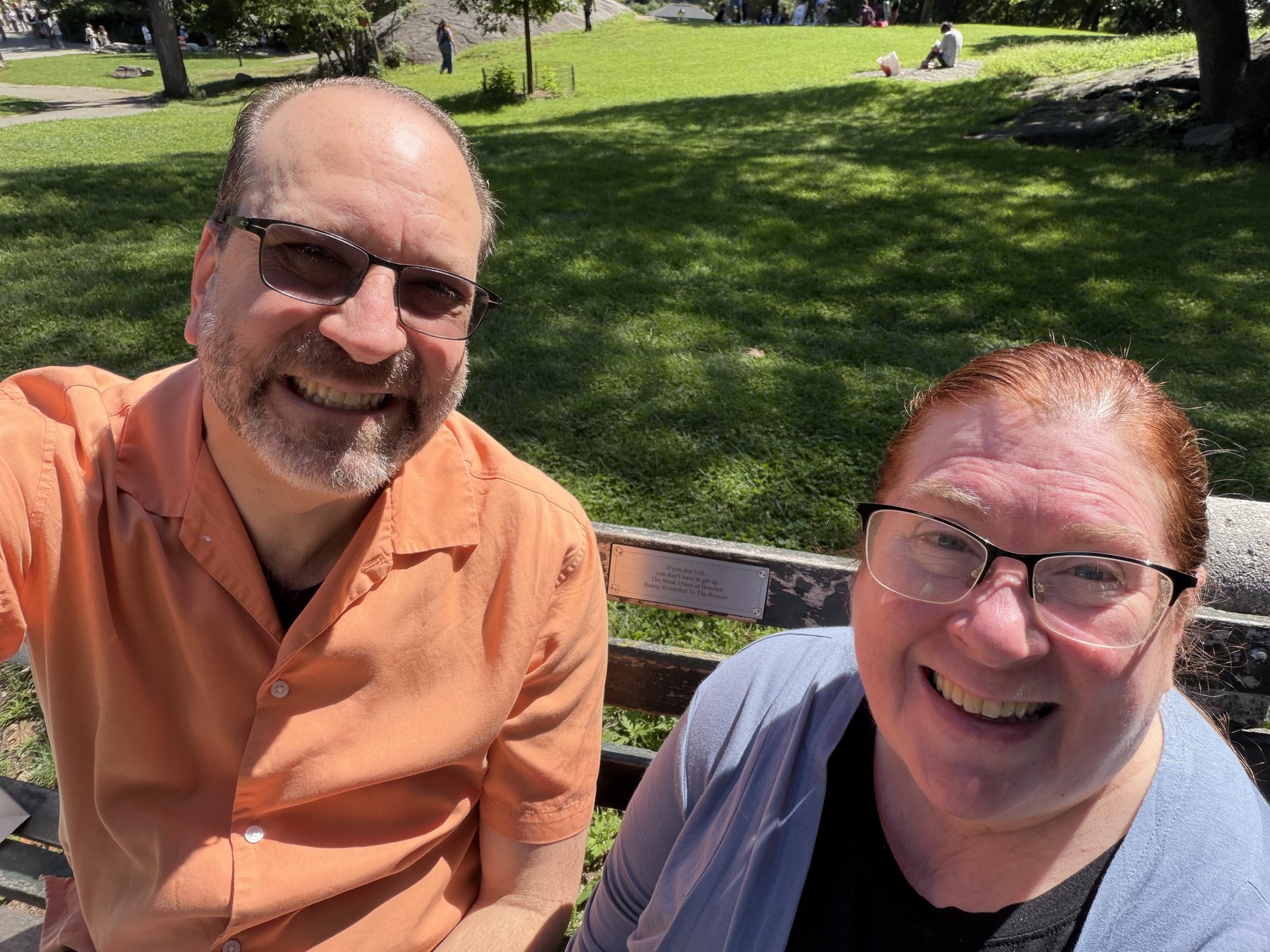 Two smiling visitors taking a sunny selfie at Bunny's bench