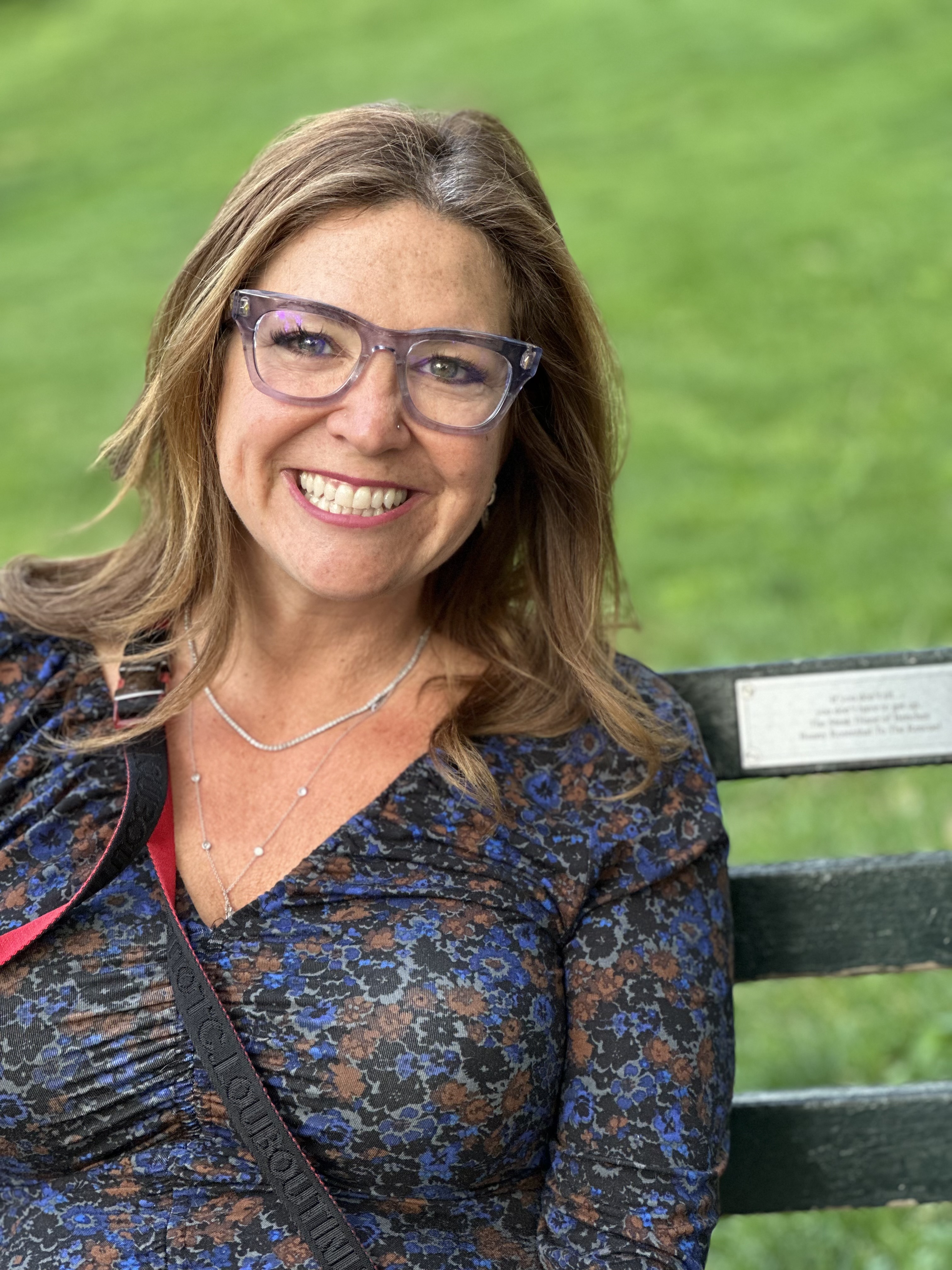 A smiling visitor sitting beside Bunny's bench plaque